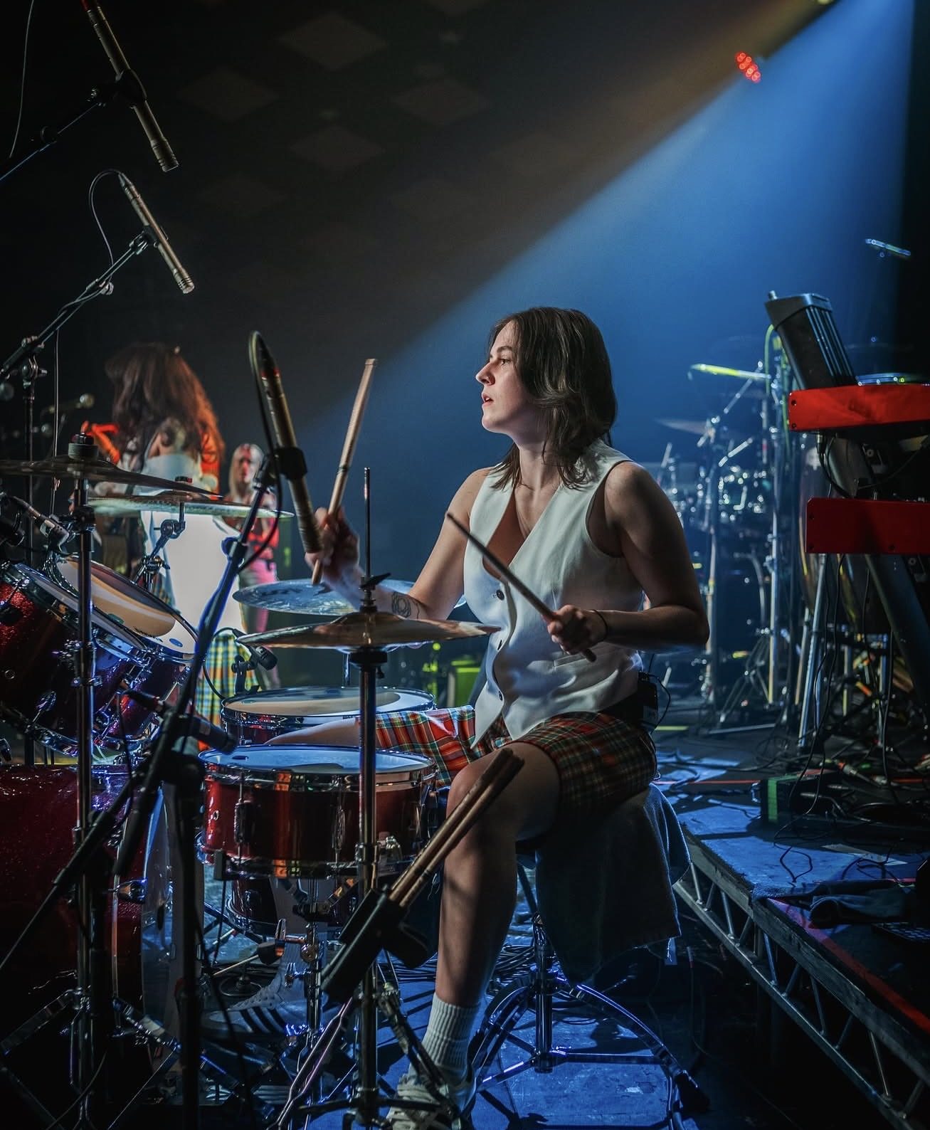 ACB playing drums under a blue stage light